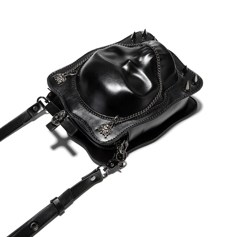 Black mini square crossbody bag with embossed skull design, metal chain strap, and zip opening.