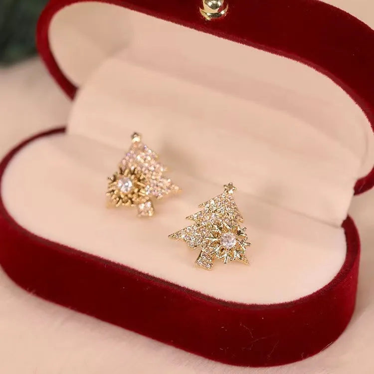 Pair of rotatable Christmas tree stud earrings with rhinestone snowflake detail in gold on a white background