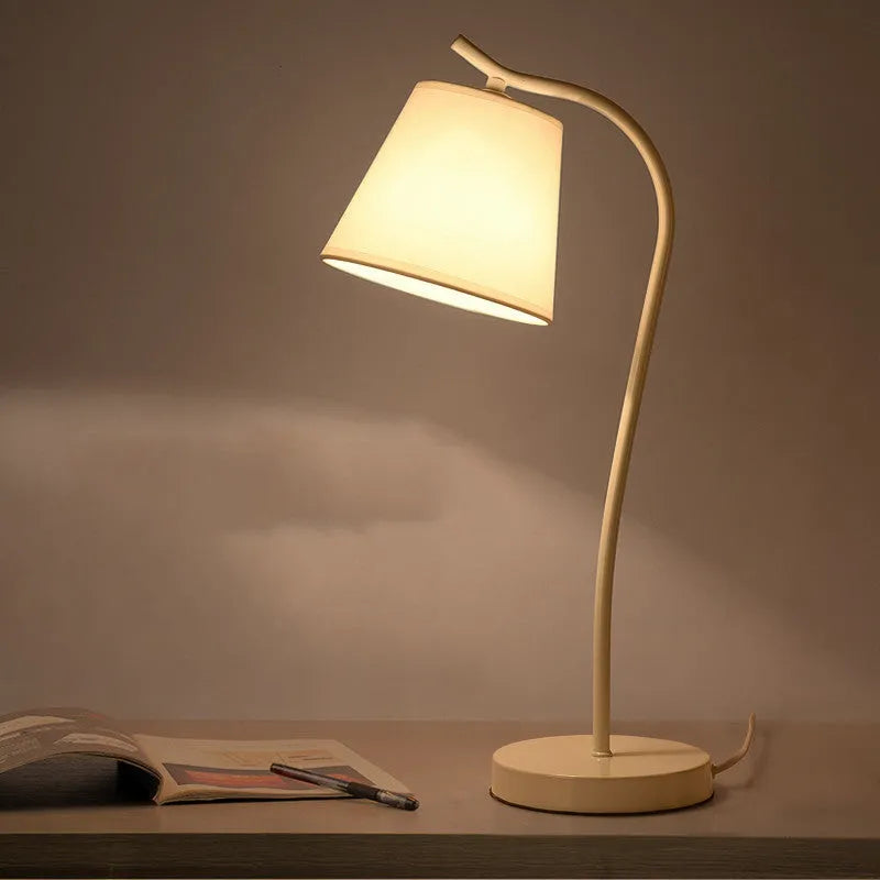 A simple modern Nordic style LED desk lamp with a dimmer switch on a desk.