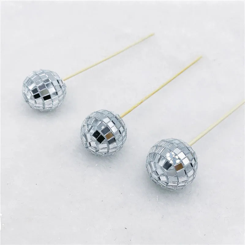 Small glass mirrored disco ball cake decoration attached to a thin wooden stick.