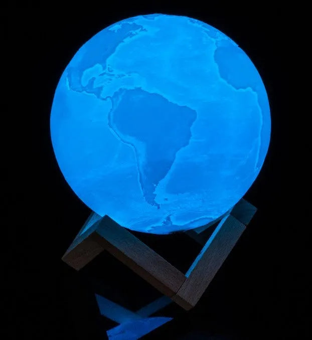 3D printed white moon lamp on a wooden holder, showing detailed lunar surface and a glowing yellow light.