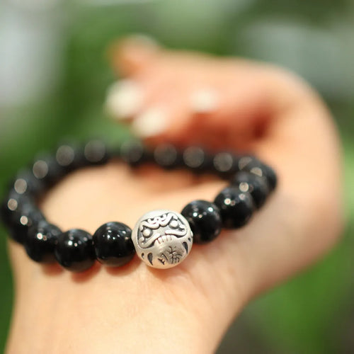 Close-up of a black agate bead bracelet with a sterling silver adjustable clasp on a wrist.