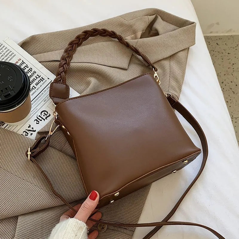 Retro style khaki crossbody bucket bag with weaving detail on the front.