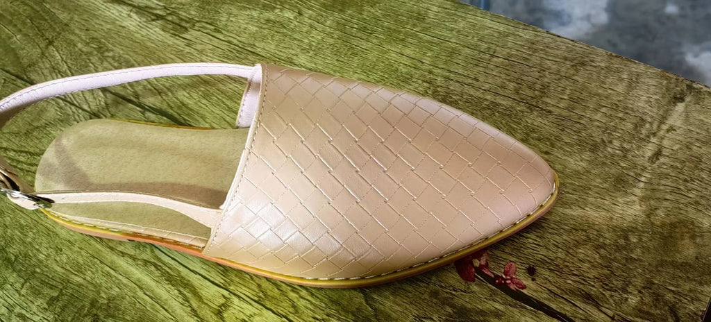 A pair of black baotou flat sandals with a buckle fastening and a pointed toe on a rubber sole.