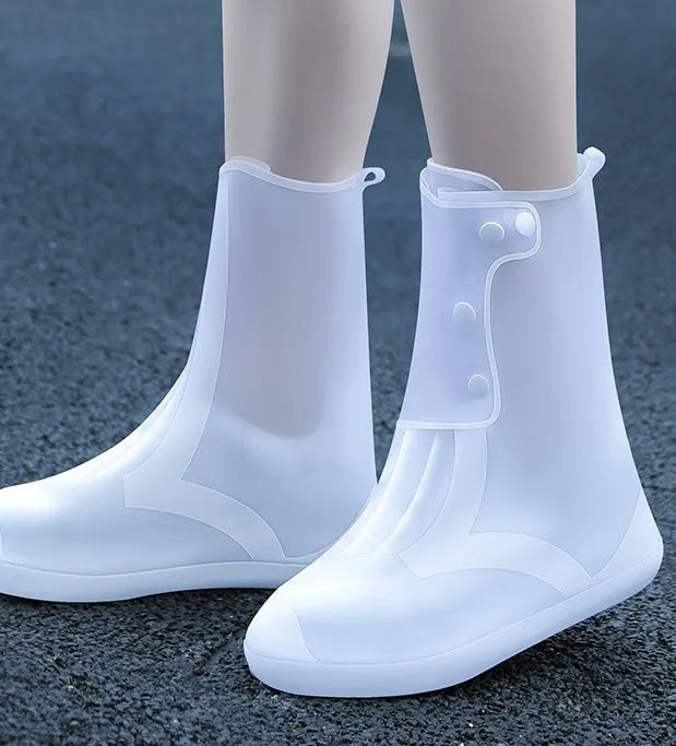 White high-top reusable PVC waterproof shoe covers with anti-skid sole on a wet surface.