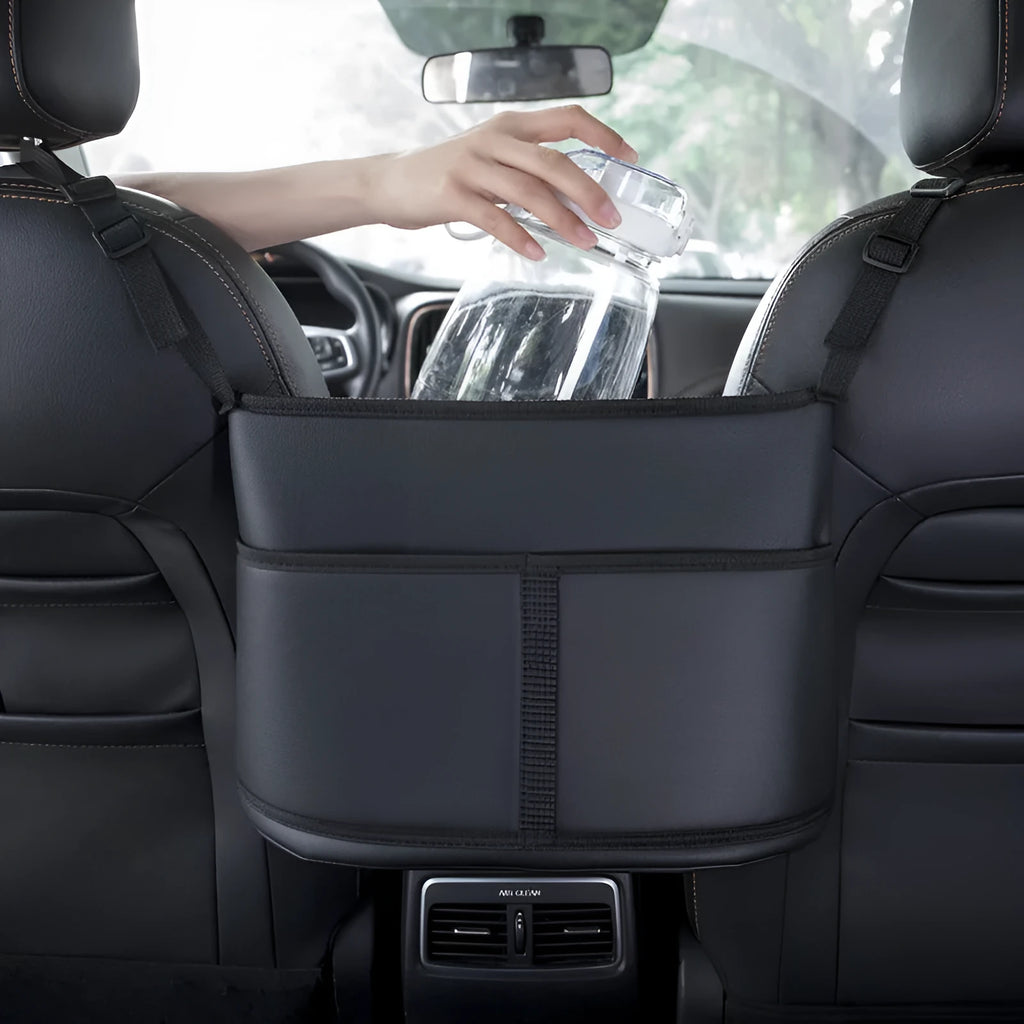 Black leather car seat organiser bag with carbon fibre pattern, shown in a car's centre seat gap.