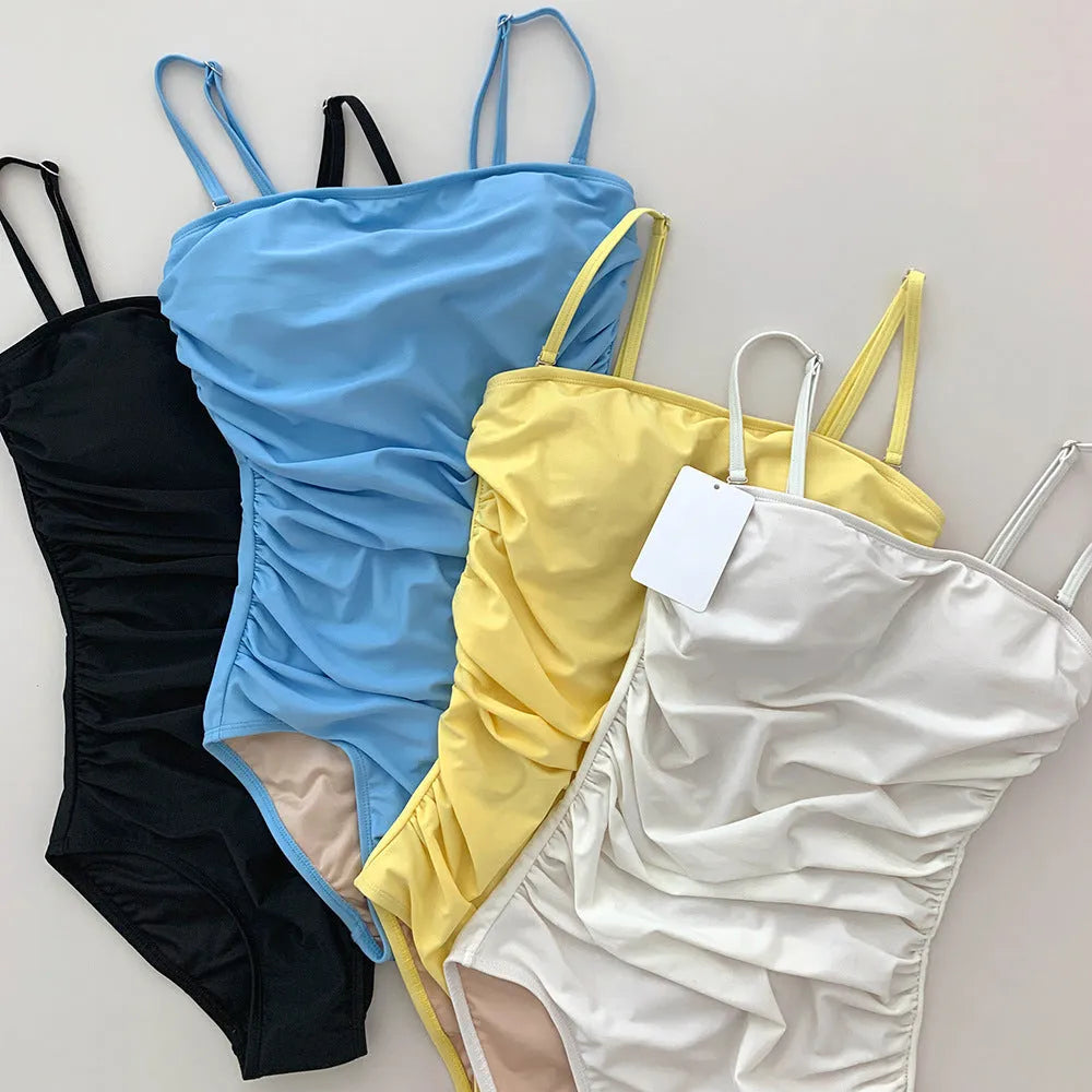 Blue sling style one-piece swimsuit with belly pleating on a model