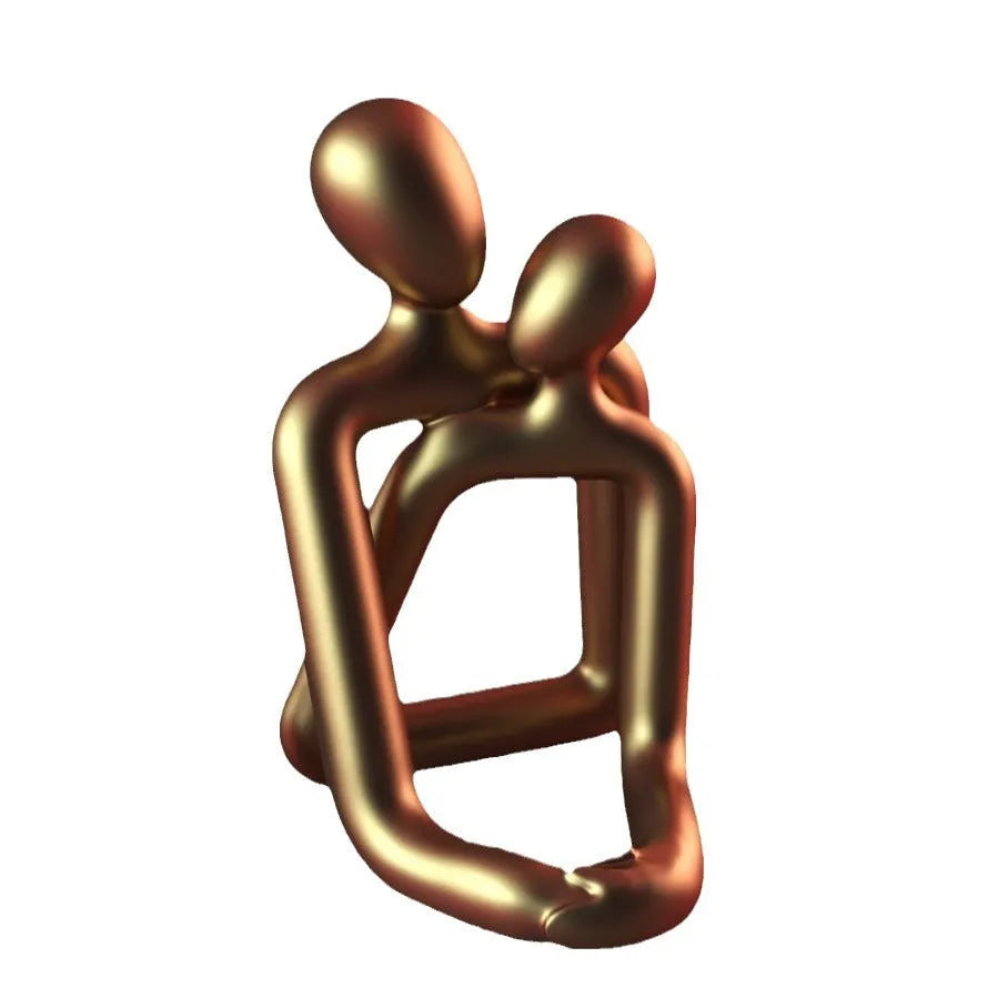 Modern resin couple statue in milky white or gold colour on a wooden surface.