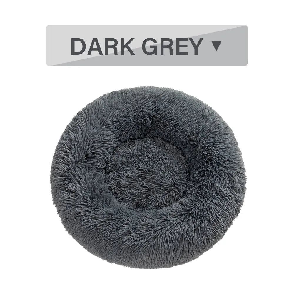 Fluffy grey donut-shaped dog bed with high plush sides on a wooden floor.