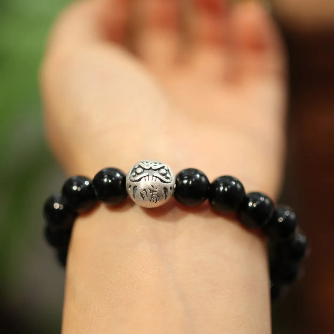 Close-up of a black agate bead bracelet with a sterling silver adjustable clasp on a wrist.