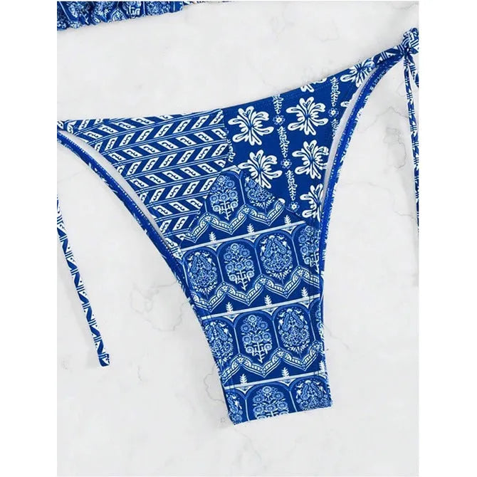Women's green split bikini swimsuit with bandage-style stitching on a beach.