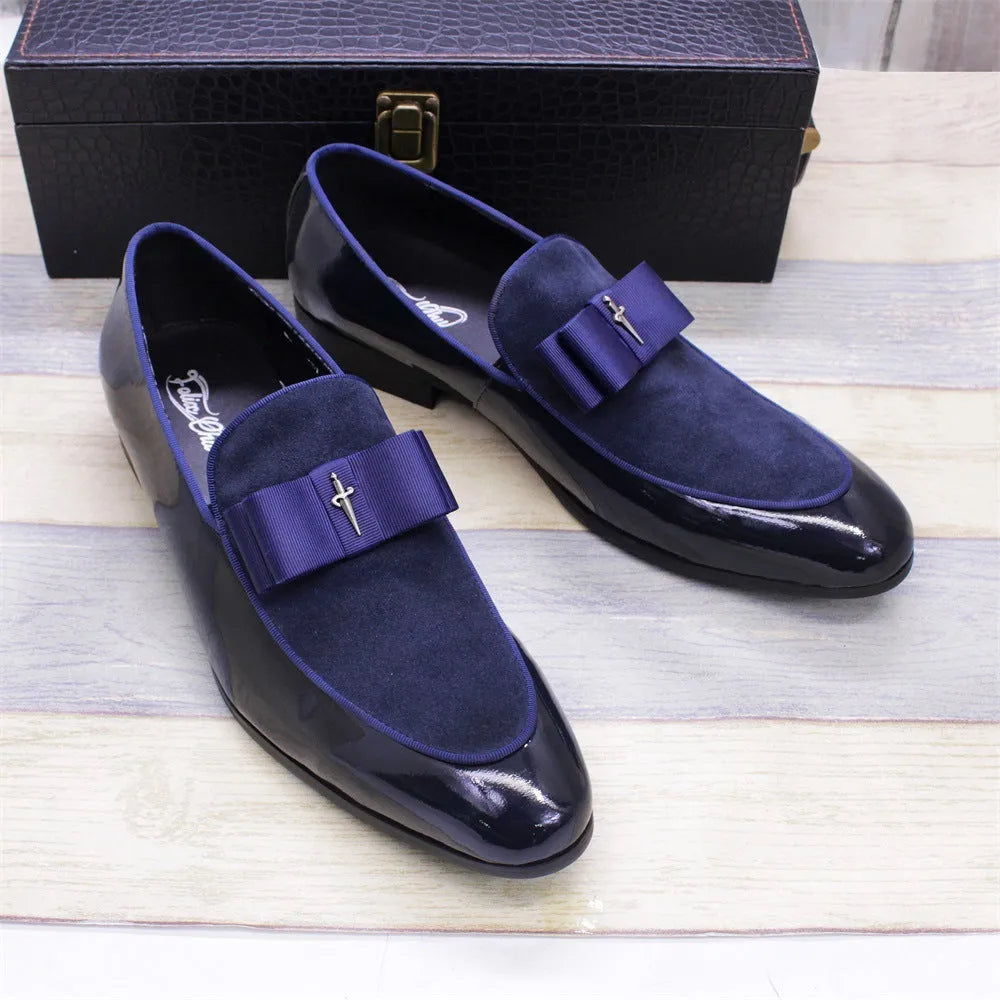 Men's black and brown tassel loafers with a matte and patent leather upper on a wooden floor.
