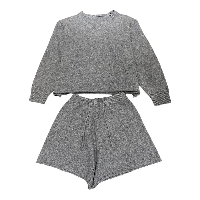 Woman wearing a loose-fit long sleeve knitted sweater and matching high-waisted wide-leg shorts in a neutral colour.