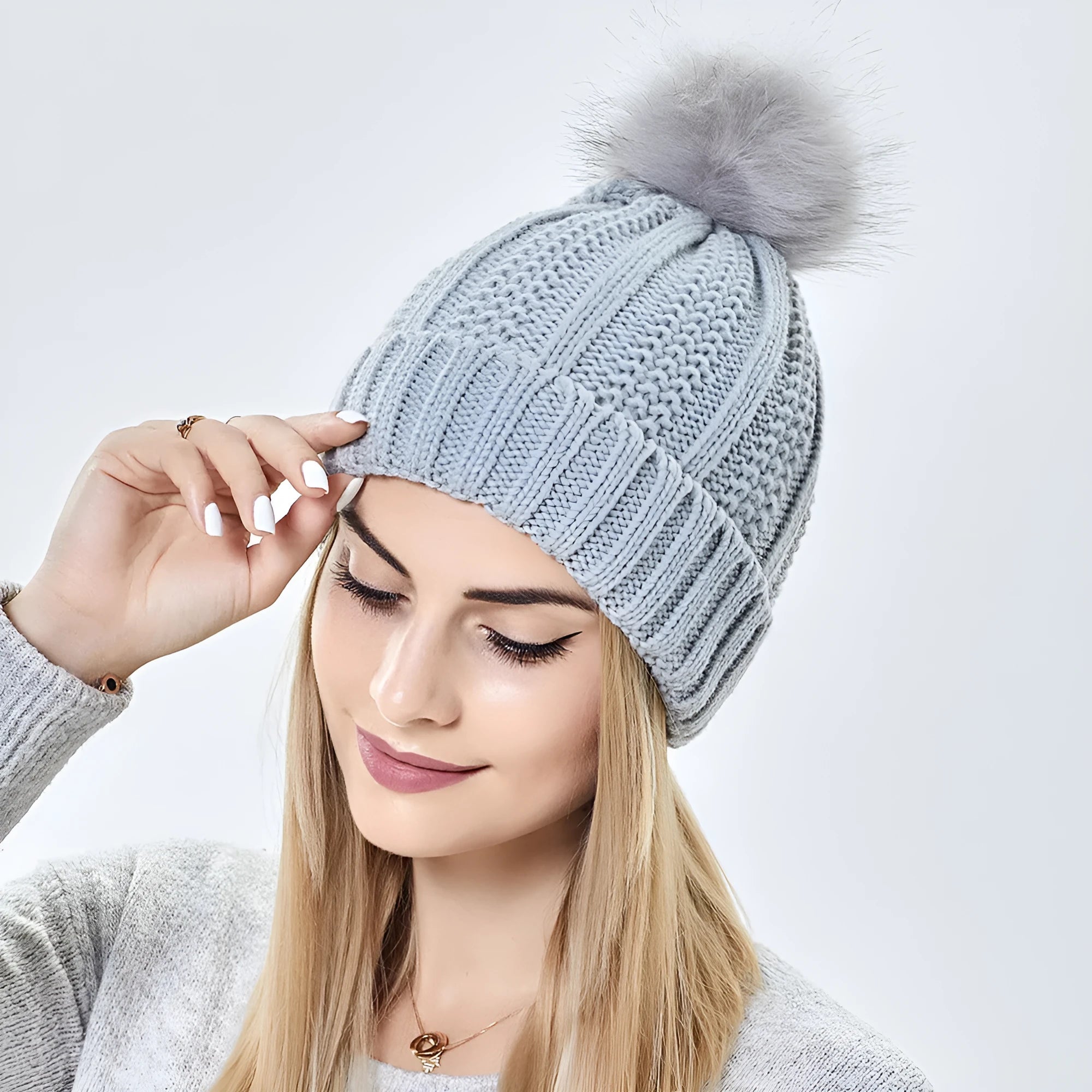 Women's knitted beanie hat with faux fur pom pom and satin lining in multiple colour options.