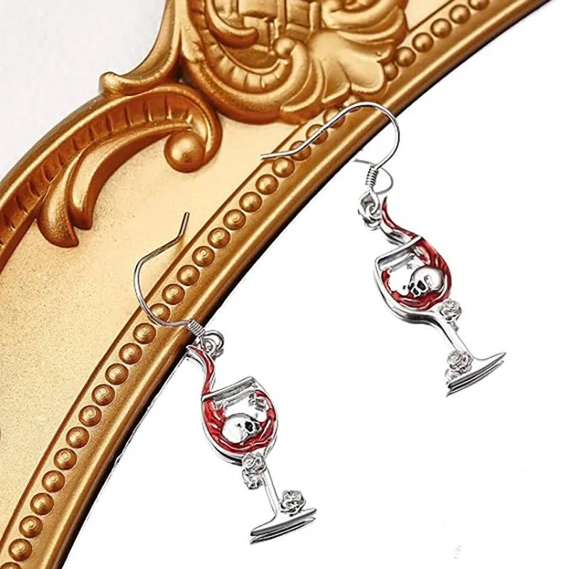 A pair of silver-toned drop earrings featuring a detailed geometry skull design combined with a wine glass shape.