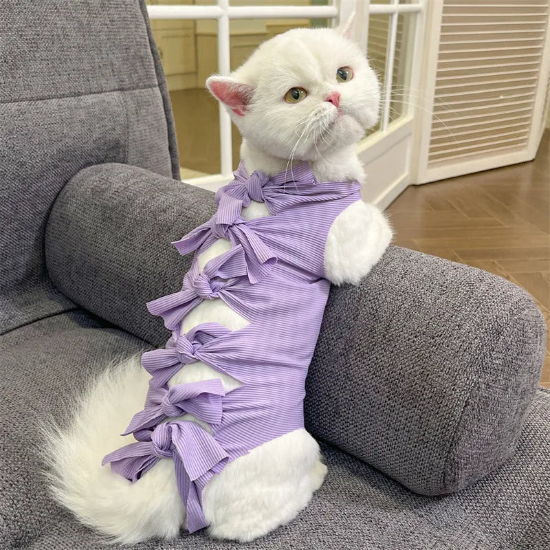Pink lace-up cat recovery bodysuit on a table, showing back ties and full-body design for post-surgery care.