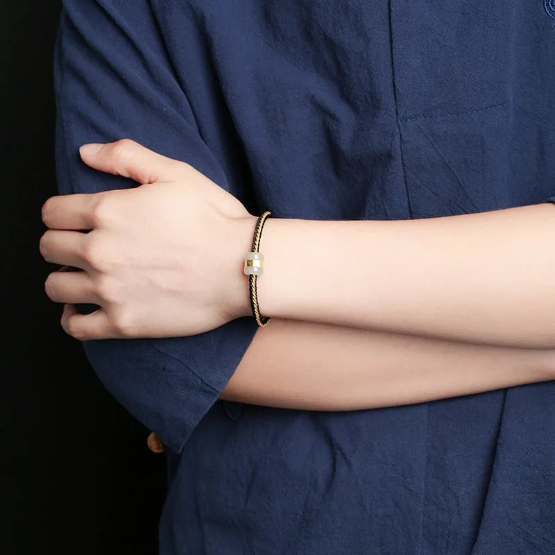 Hand-woven bracelet with Hetian jade inlay gold tone finish geometric shape on dark background