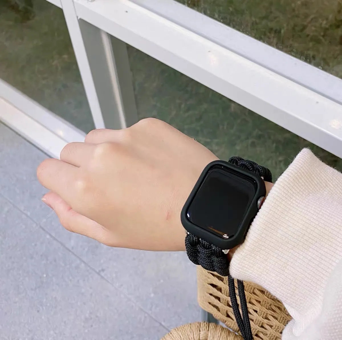 Paracord braided smartwatch strap in black on a watch, showing textured weave and connector lugs.