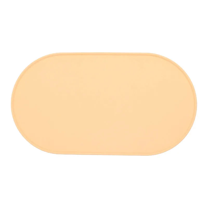 Green silicone cat feeding mat with raised edge under a ceramic bowl on a wooden floor
