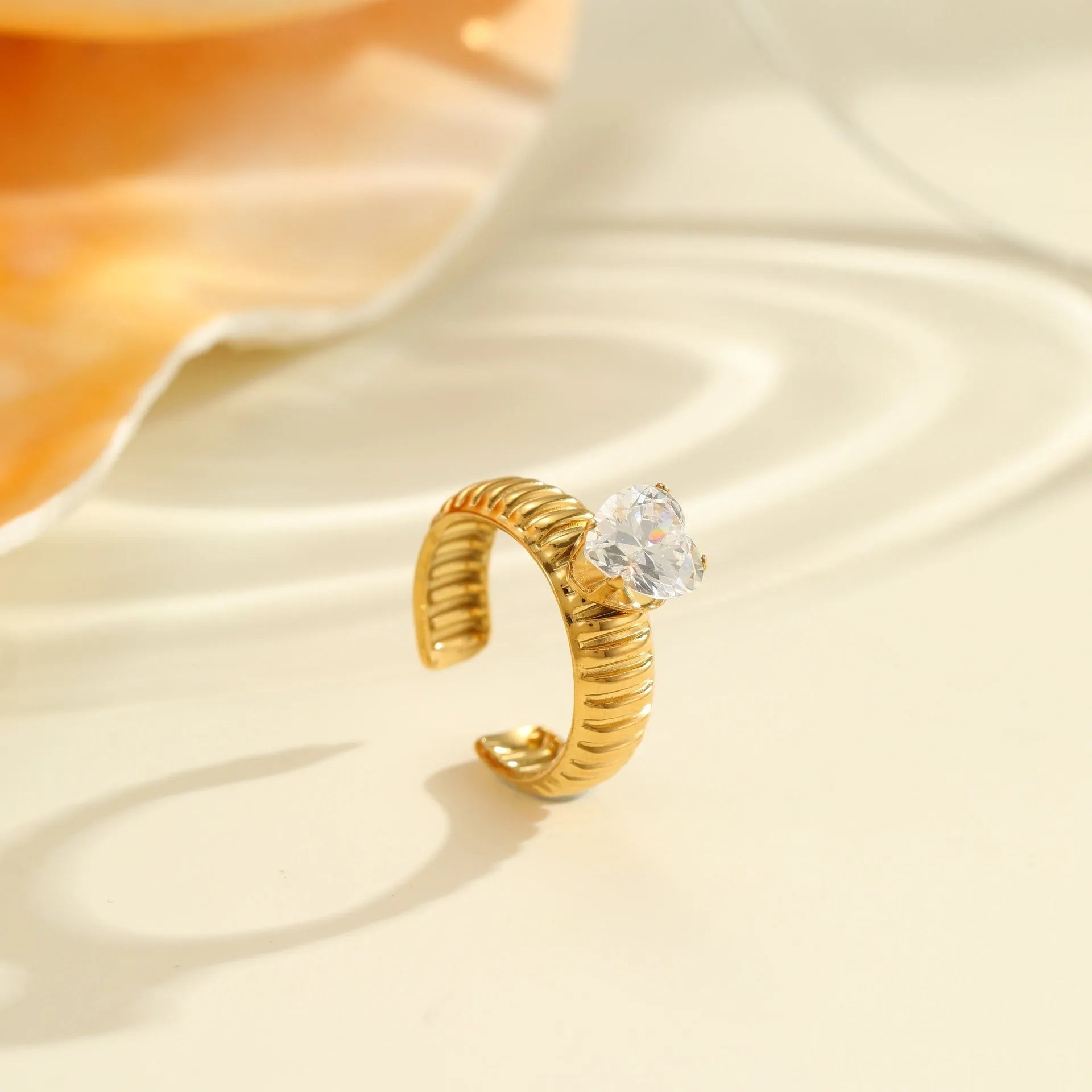 Gold electroplated adjustable ring with geometric zircon design on a stainless steel band.
