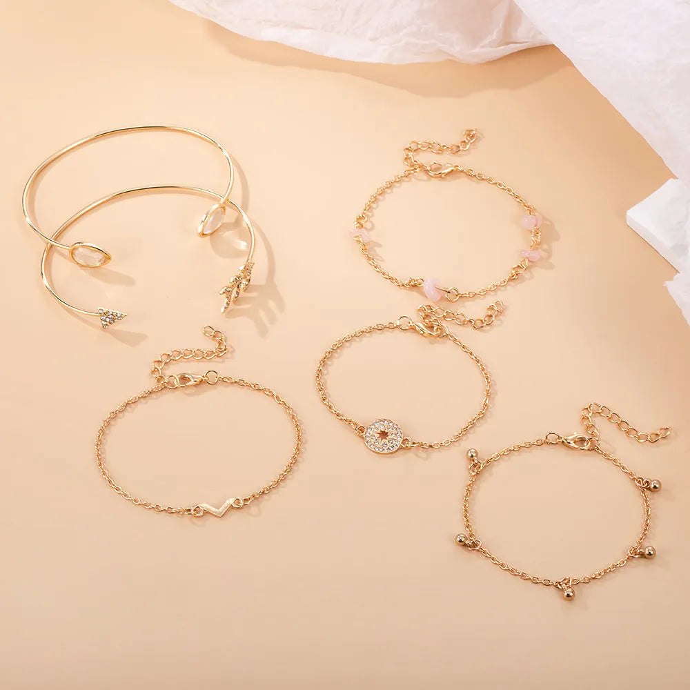 Set of six gold bracelets with arrow, water drop, and V shapes featuring spot drill detail.