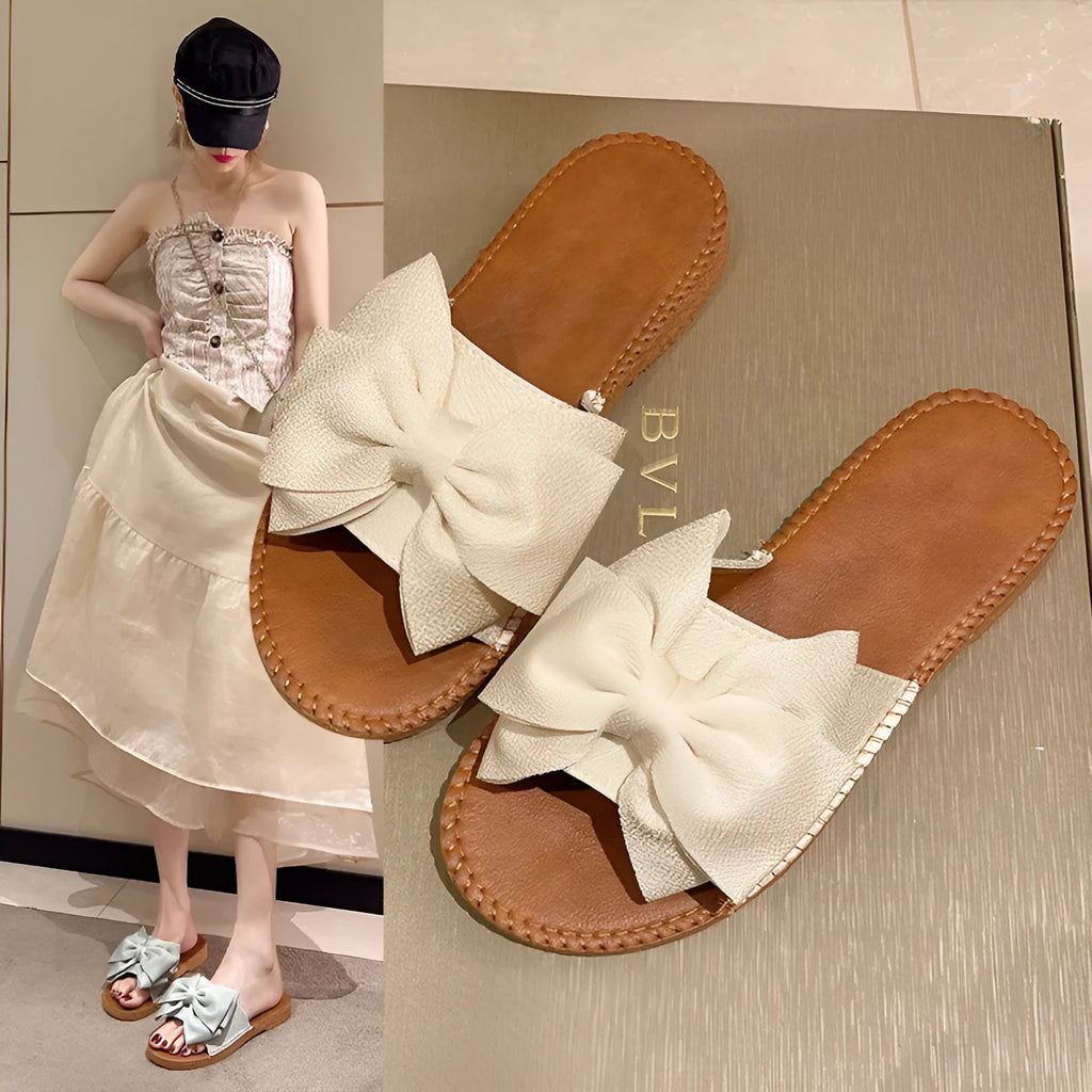 Women's beige slip-on cloth sandals with a bow on the upper and a soft flat rubber sole.