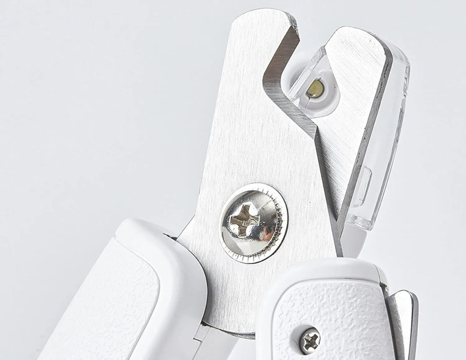 White pet nail clippers with LED light and transparent anti-splash guard next to a nail file on a table
