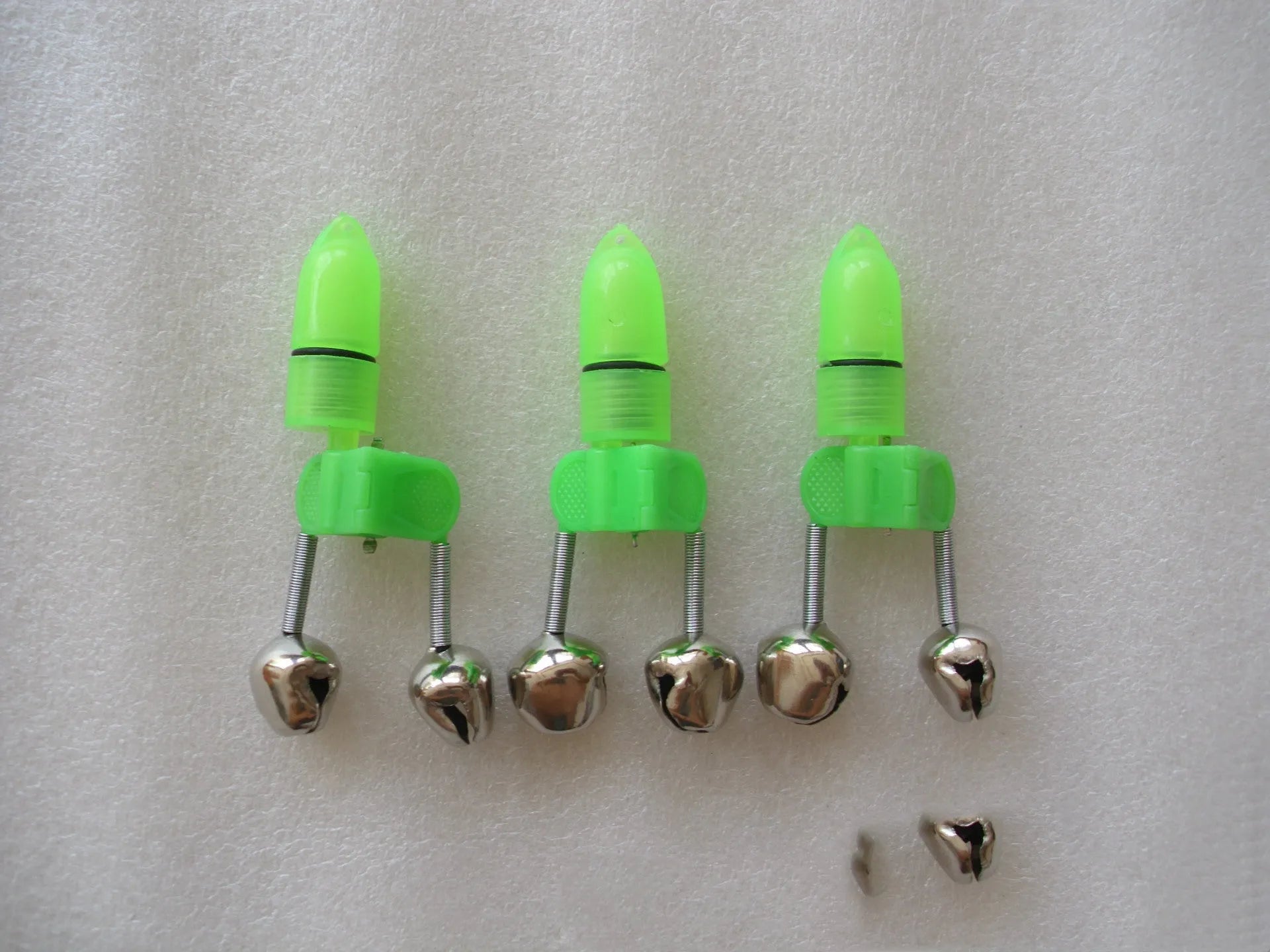 Two fishing bell bite alarms with LED lights, one green one red, clipped onto a fishing rod tip