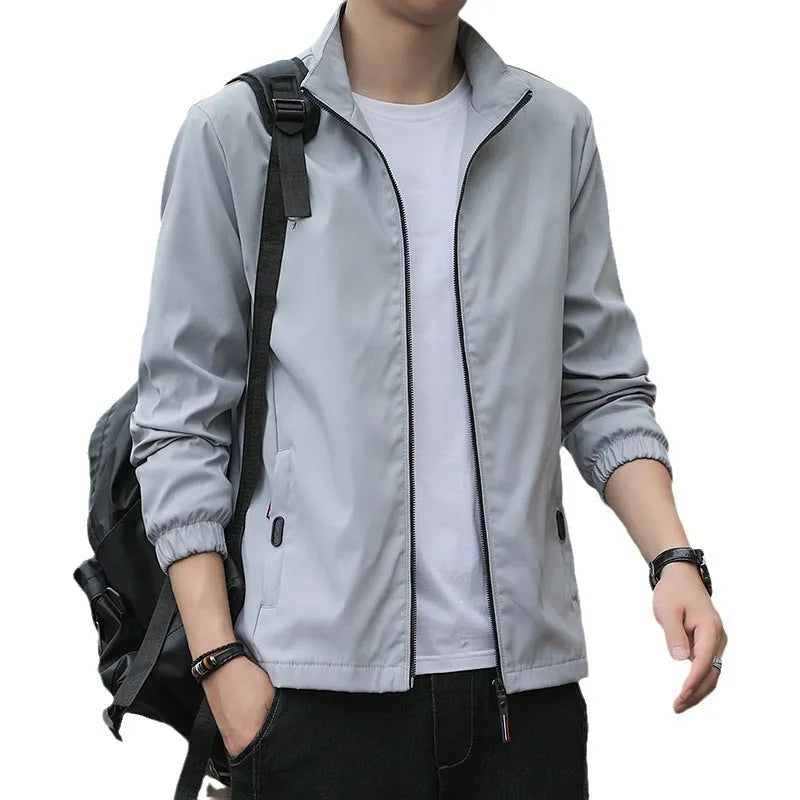 Man wearing a loose-fit black casual autumn jacket with a lapel and zippered pockets.