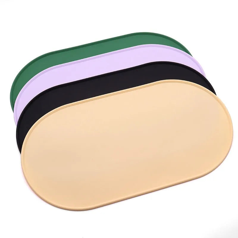 Green silicone cat feeding mat with raised edge under a ceramic bowl on a wooden floor