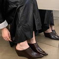 Women's black Wind Wedge closed toe half slippers with PU upper on a wooden floor.