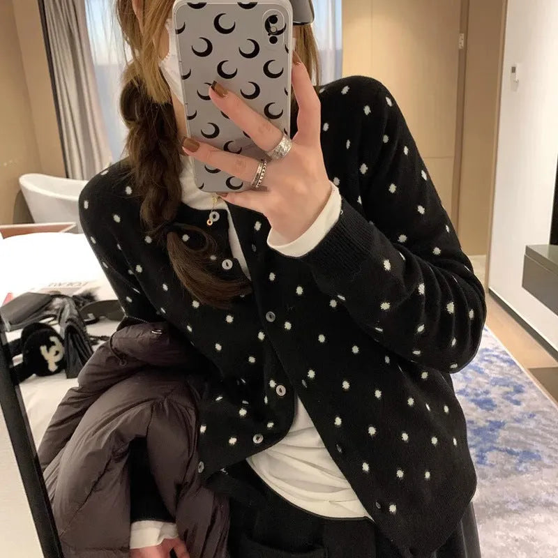 Women's loose grey dot patterned knitted cardigan with crocheted flower details on the front.