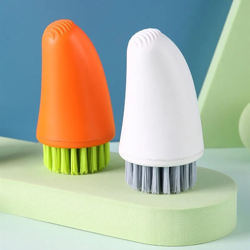 Orange and white carrot-shaped nylon kitchen cleaning brush on a plain background.