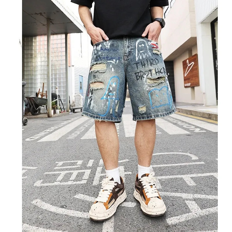 Men's blue ripped jeans shorts with straight leg cut, zipper fly, and graffiti detailing