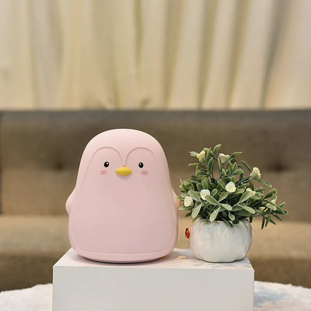 Soft white silicone penguin-shaped rechargeable night light on a surface.