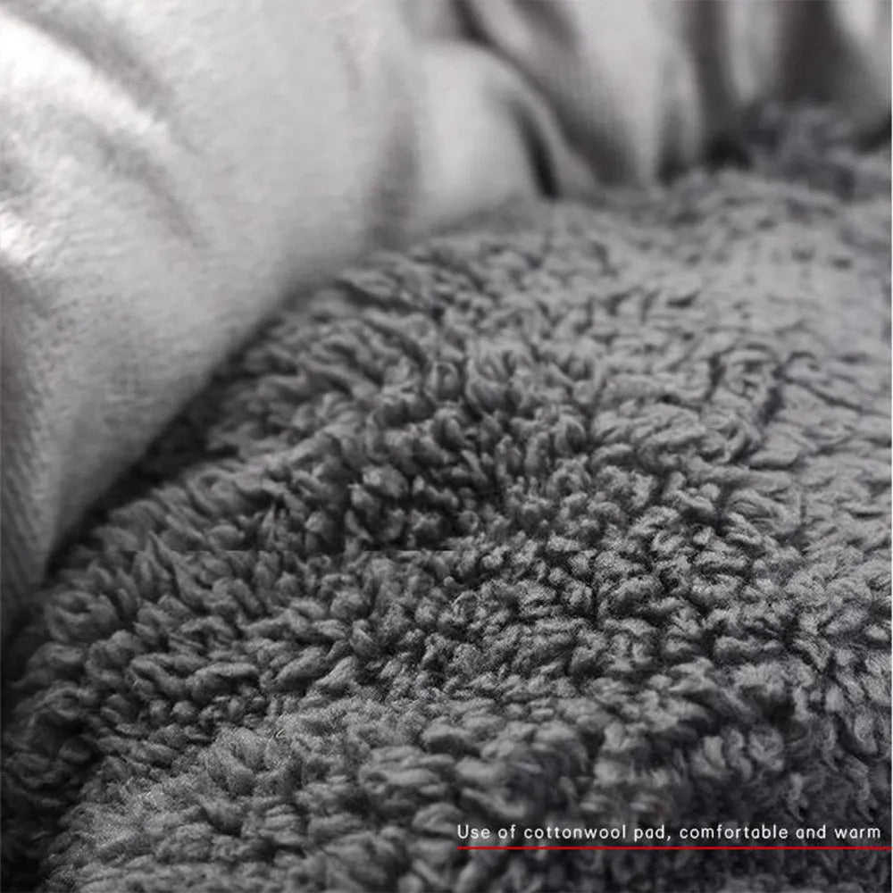 Grey round plush pet bed with raised edge and pillow, shown on a non-slip base.
