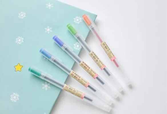 Set of twelve black Muji retractable gel pens with 0.5mm tips, laid out on a notepad.