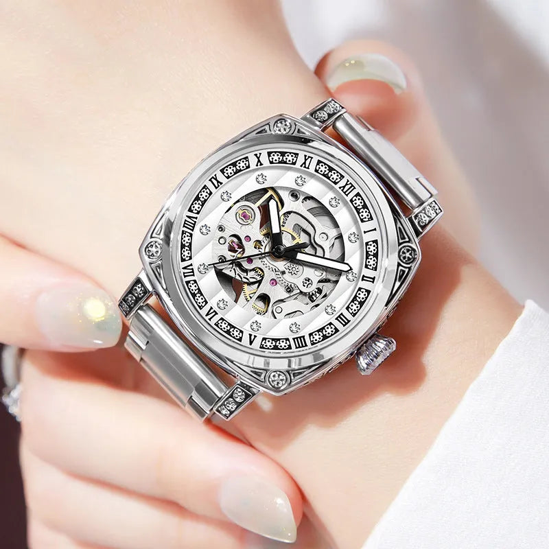 Men's black leather strap mechanical watch with luminous hands on a wrist.