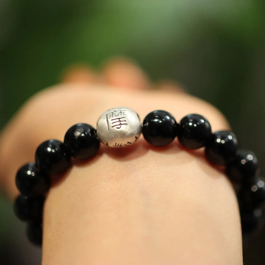 Close-up of a black agate bead bracelet with a sterling silver adjustable clasp on a wrist.