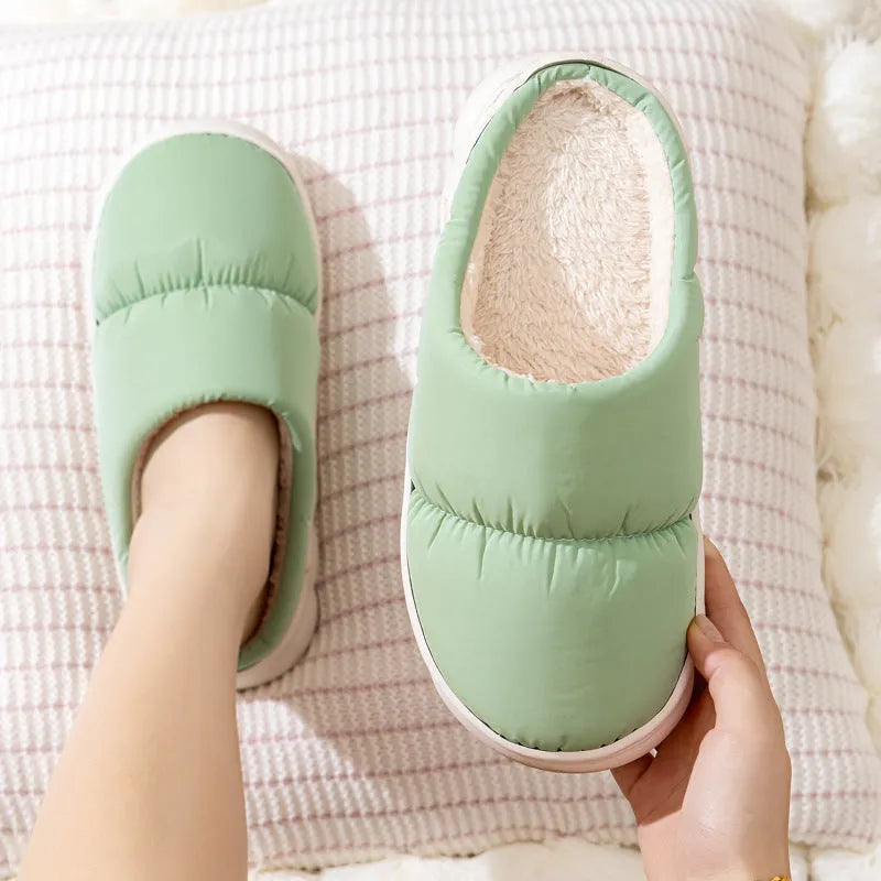 Blue down cotton winter slippers with a thick rubber sole and plush lining, shown on a wooden floor.