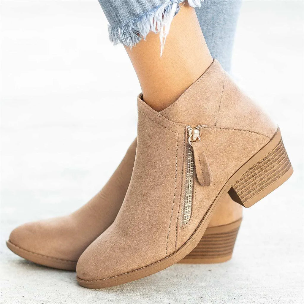 Women's beige suede ankle boots with a side zip and chunky heel on a plain background.