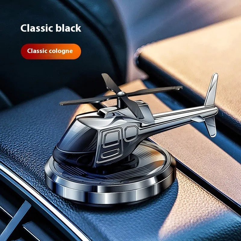 Silver metal solar-powered helicopter car air freshener rotating on a dashboard