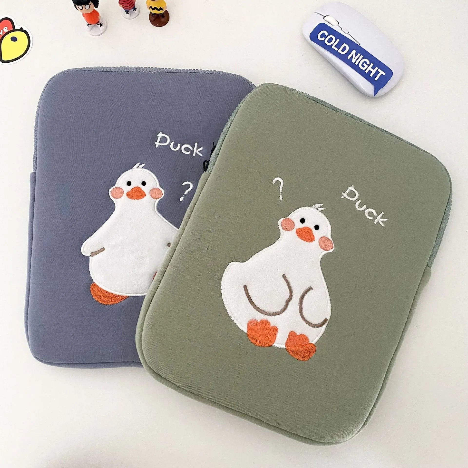 Blue cotton tablet case with embroidered cartoon duck design and a black zipper, shown open.