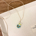 Women's necklace with coloured glaze skirt joker pendant on a beige cotton and linen chain, 45cm long.