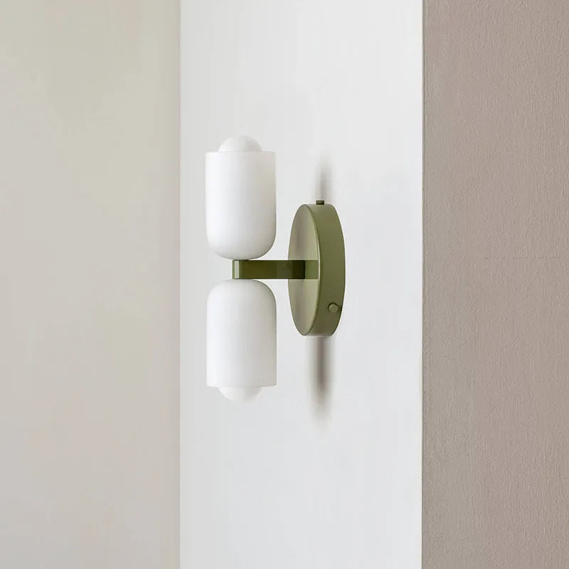 Cream base double head wall lamp with white glass shades against wall