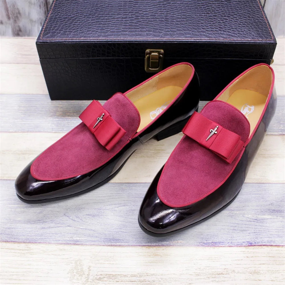 Men's black and brown tassel loafers with a matte and patent leather upper on a wooden floor.