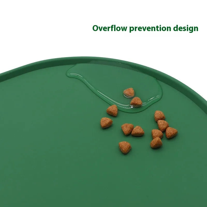 Green silicone cat feeding mat with raised edge under a ceramic bowl on a wooden floor