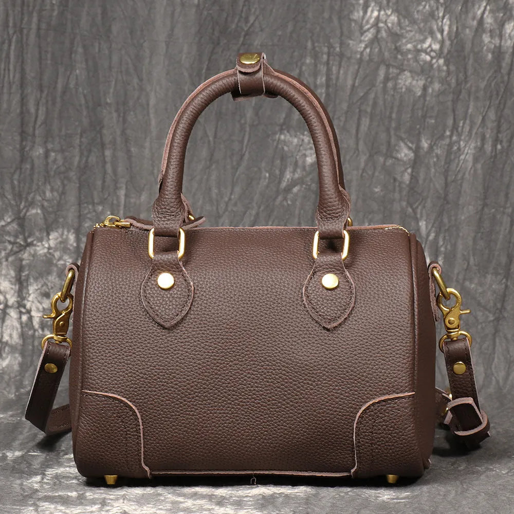 Brown yellow cowhide leather Boston bag with single shoulder strap, showing cylindrical shape and open outer pocket.