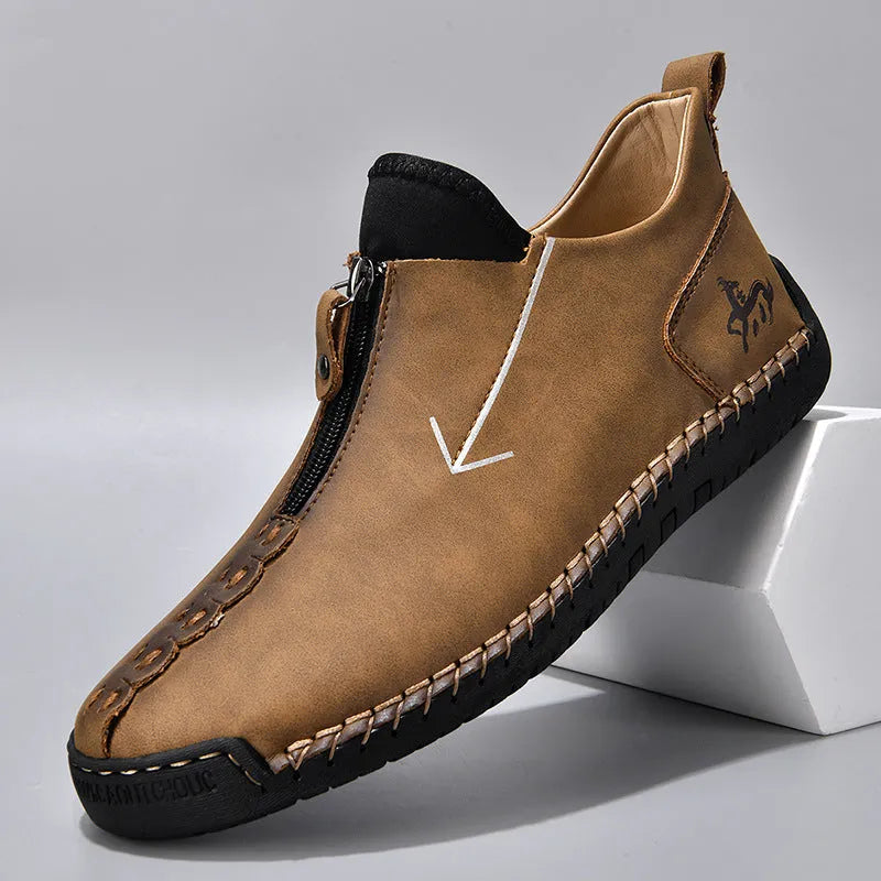 Men's black leather ankle boots with a front zip and hand-stitched detailing on a rubber sole.