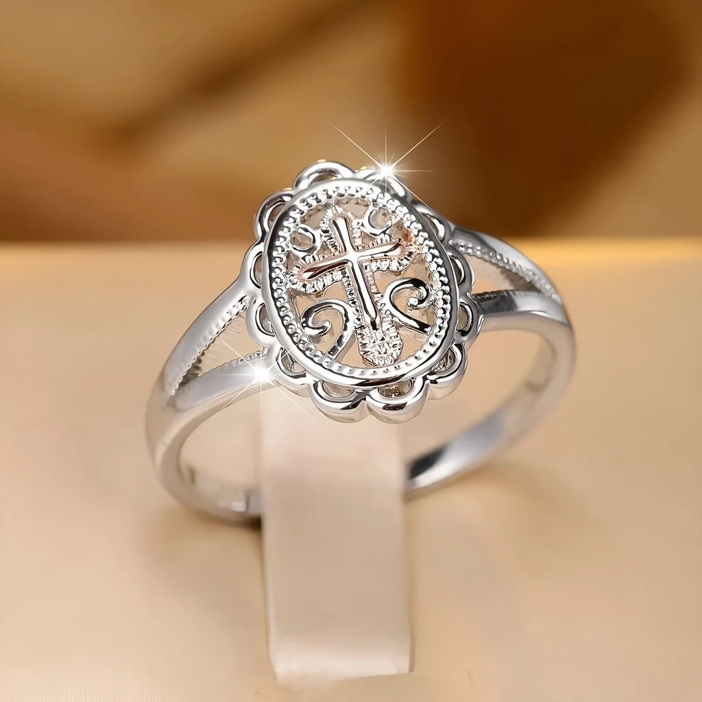 Silver women's ring with detailed cross and lace pattern, shown on a finger.